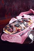 Süsser Auflauf mit Brioche, Blaubeeren und Pflaumen in der Form