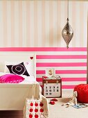 Pinkfarbene Quer- und pastellige Längsstreifen hinter Landhausbett und Nachttischkiste im Kinderzimmer