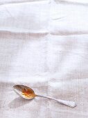 A spoon with the remains of food on a white linen cloth