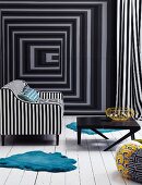 Black and white upholstered armchair and black coffee table on a white wood flooring in front of a wall with optical illusion wallpaper