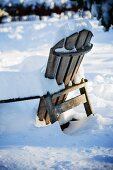 Mit Schnee bedeckter Holzstuhl im Garten