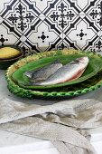 Two raw fish on a green ceramic plate