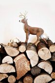 Kleine Plastik-Hirschfigur und silberne Christbaumkugeln auf gestapeltem Brennholz