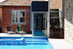Renovated house with brick, glass and stone facade; garden pool with connection to interior pool