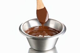 Melted chocolate in a bowl with a wooden spoon