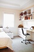 Guest room with chest of drawers below integrated, continuous desk top and books on wall-mounted shelves