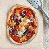 A pizza with quail's eggs, red onions, parmesan and radicchio