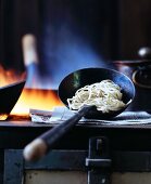 Oriental egg noodles in a ladle on a stove