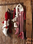 Baby clothes with festive motifs hanging from pegs on rustic wooden wall