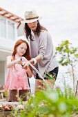 Mutter und Tochter gießen Blumen im Garten