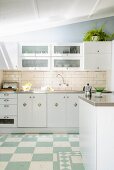 Modern kitchen with stainless steel worksurfaces; tiled splashback and cup handles on base units lend a vintage atmosphere