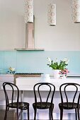 Pattern of circles on cylindrical lampshades above breakfast bar and black Thonet chairs