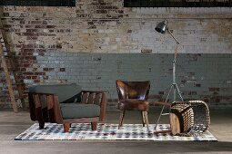 Armchairs, tipped over wooden chair and retro standard lamp against old brick wall