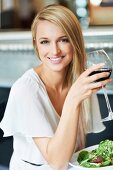 Frau trinkt ein Glas Rotwein beim Mittagessen im Restaurant
