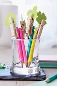 Coloured pencils topped with clothes pegs holding paper shamrock leaves