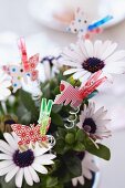 Paper butterflies attached to flowers with clothes pegs