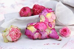 Decorative heart made from bound rose petals and rose blooms on monogrammed linen cloth