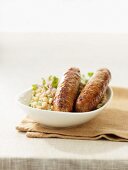 Bratwurst sausages on a bed of risotto made with soft wheat