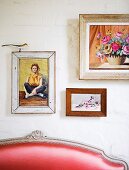 Framed pictures on wall above partially visible backrest of couch with red leather cover and Rococo wooden frame
