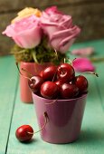 A still life featuring fresh cherries and an arrangement of roses