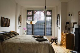 Doppelbett mit Fell-Tagesdecke, im Hintergrund Fenster mit geschlossenem Rollo in folkloristischem Ambiente