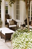 A grand villa - plant pots filled with white blooming flowers in front of brown wicker outdoor furniture on a terrace