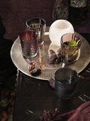 Tablett mit getrockneten Datteln, Gläsern und Teelichthalter auf einem dunklen Tisch
