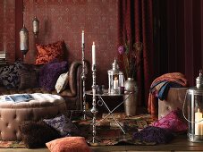 Living room in the Bohemian Look: pillows on the floor and on a leather sofa, upholstered table, side table and silver candlesticks