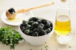 Schwarze Oliven in einer Schale mit Petersilie und Olivenöl