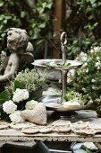 weiße Hortensien, selbstgemachte Jutesäckchen & Häkeldeckchen neben Etagere auf Gartentisch