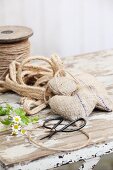 Hand-sewn decorative hearts made from old hessian, parcel string, Chinese scissors and chamomile flowers on old table