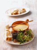 Cheese fondue with white bread and frisee salad with walnuts