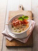 Garlic soup with pesto and bacon kebab