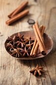 Star anise and cinnamon sticks in a dish on a wooden surface