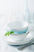 Stacked dinner bowls and plates, drinking glasses and forks