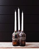 Candles in beer bottles covered in dripped wax with Christmas-tree tag