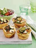 Mini tartlets filled with sweet potato, vegetables, sausage and feta
