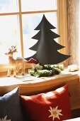 Cushions with edelweiss motif next to stylised fir tree, fly agaric toadstool, moss and fir cones