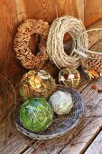 Advent arrangement of decorative spheres and hand-crafted wreaths on weathered wooden boards and leaning against wooden wall