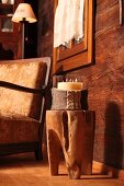 Kerzenglas mit Strick Hülle auf Baumstammhocker vor gemütlichem Armlehnensessel in Holzhütte