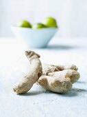 Fresh root ginger; in the background a bowl of limes