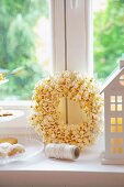 A house-shaped candle lantern, a popcorn wreath and a tiered cake stand of biscuits