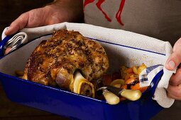 A man holding shin of veal in a roasting tin