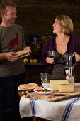 A couple eating a rustic South Tyrolean light meal with dry-cured ham, Schüttelbrot (crispy unleavened bread from South Tyrol), nuts, cheese and wine