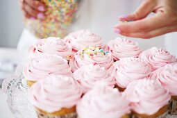 Woman decorating cupcakes with sugar sprinkles