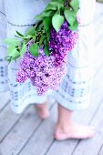 A young woman holding a bouquet of purple lilac flowers