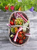 Assorted salads in a picnic basket on a wooden table