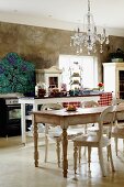 Country-house-style kitchen with shabby chic table and chairs below chandelier