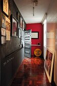 Narrow hallway with framed photos on wall painted with chalkboard paint and old mosaic parquet floor