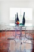 Collection of vases on glass table and Bauhaus wire chairs in minimalist ambiance